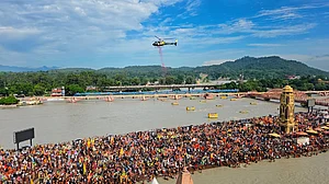 A helicopter showers flower petals on kanwariyas at Har Ki Pauri Ghat in Haridwar (photo: PTI)