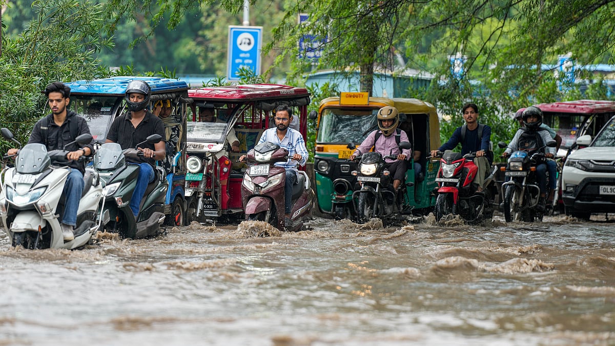Commuters wade through a waterlogged road in New Delhi on 22 July (photo: PTI)
