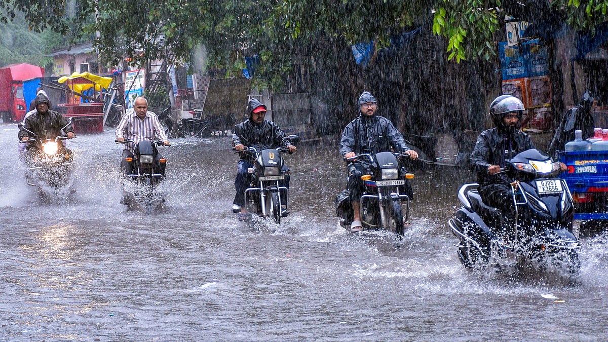 Commuters make their way through a waterlogged road in Surat (photo: PTI)
