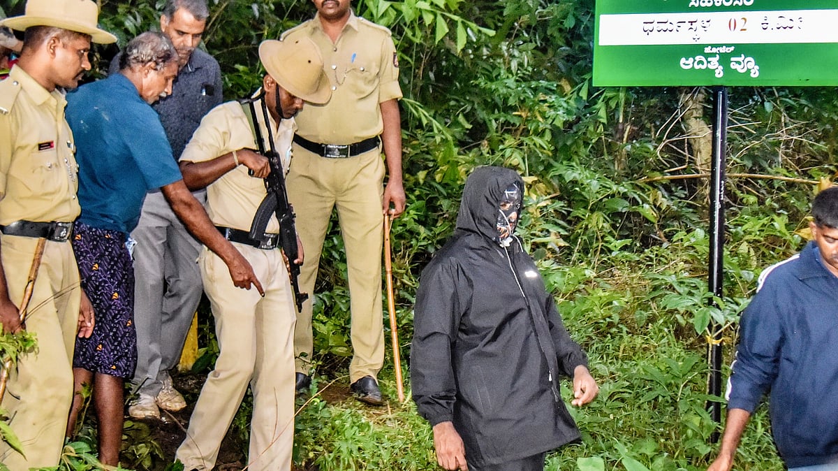 Security personnel with the whistleblower near an alleged burial site in Dharmasthala (photo: PTI)