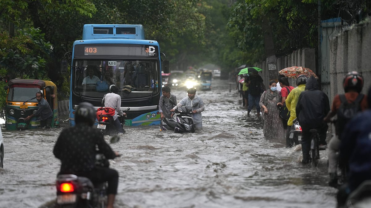 Commuters wade through a waterlogged road amid heavy rain in New Delhi on 14 August