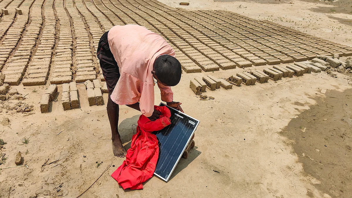 A migrant worker cleans a solar panel in Aligarh district