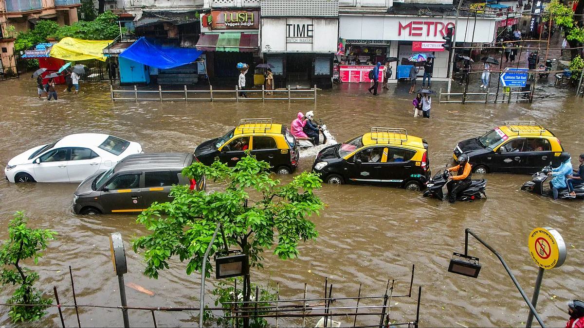 Commuters wade through a waterlogged road in Mumbai on 18 August