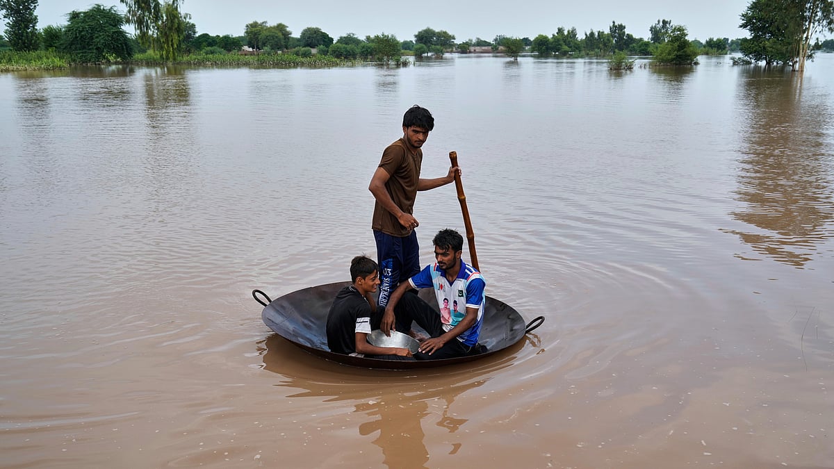 Villagers float across floodwaters on a jaggery pan-turned-raft in Jhang district