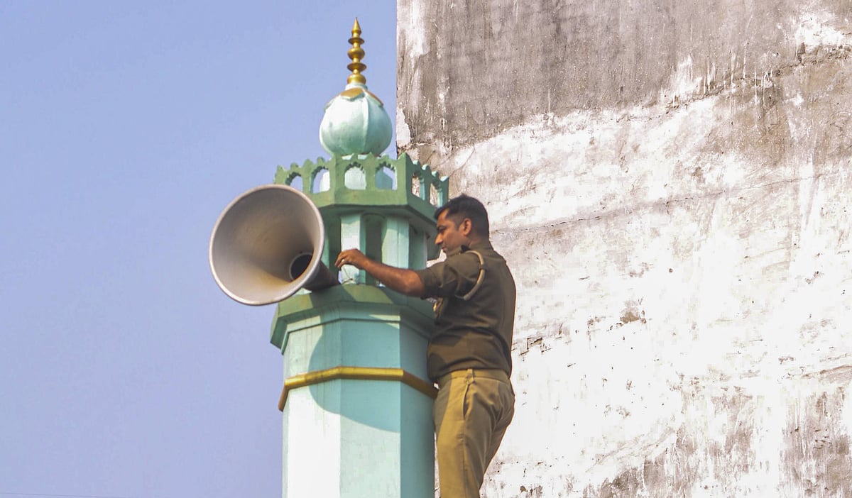 A cop removes a loudspeaker from a building during a drive against illegal loudspeakers in Lucknow.