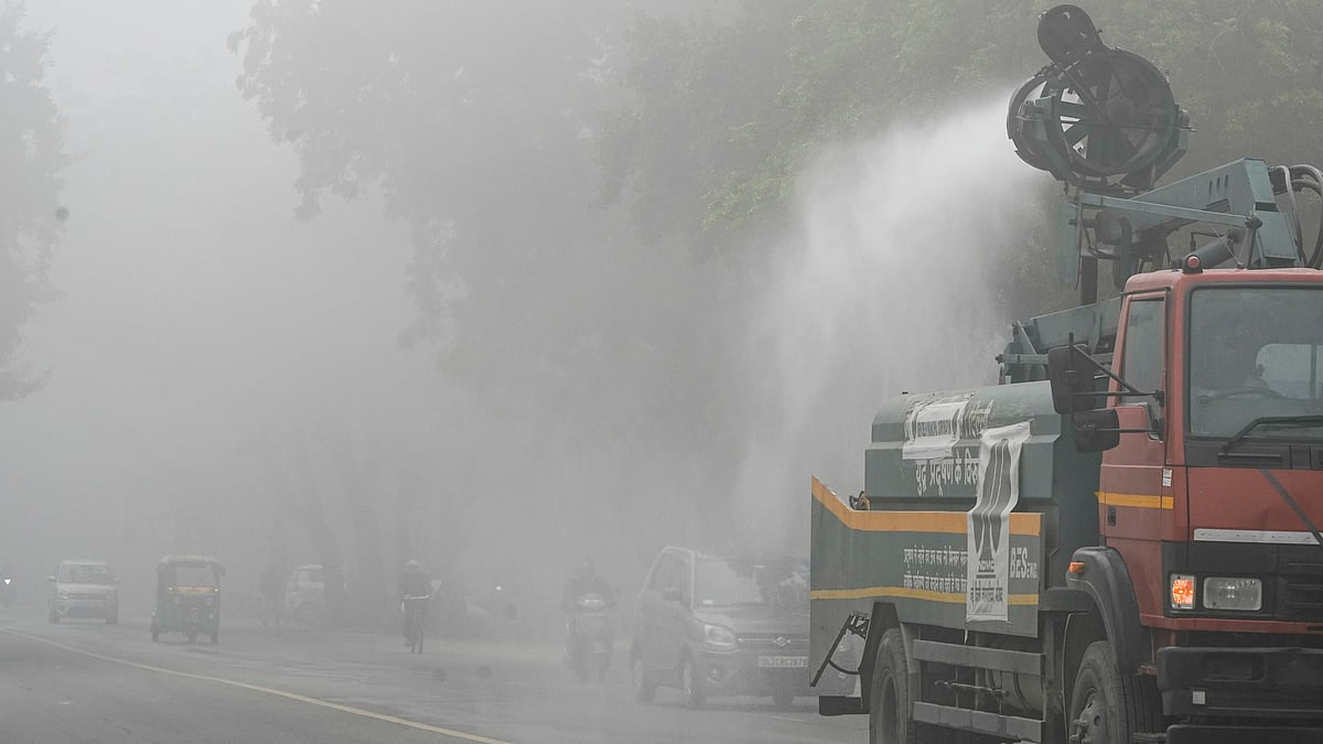 A municipal truck sprays water to curb dust amid dense fog in New Delhi.
