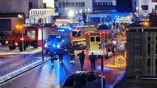 Police and fire officials stand guard outside the Swiss ski resort.