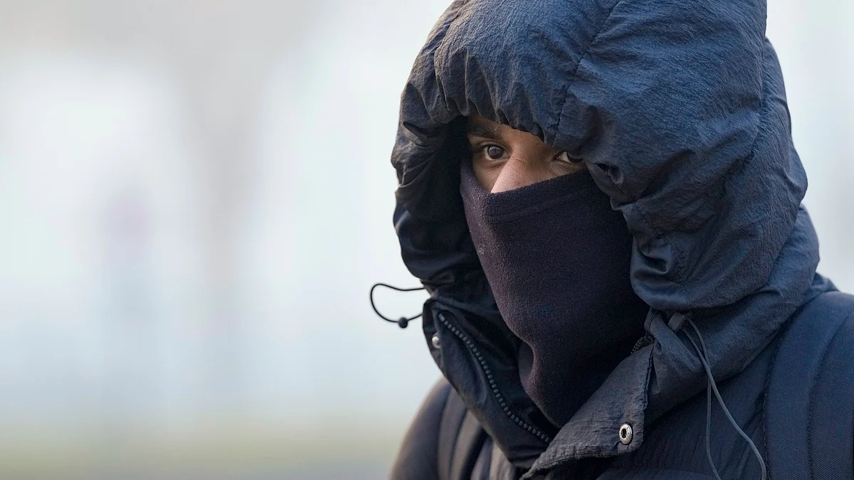 A man shields himself from the cold on a winter morning at Kartavya Path in New Delhi.