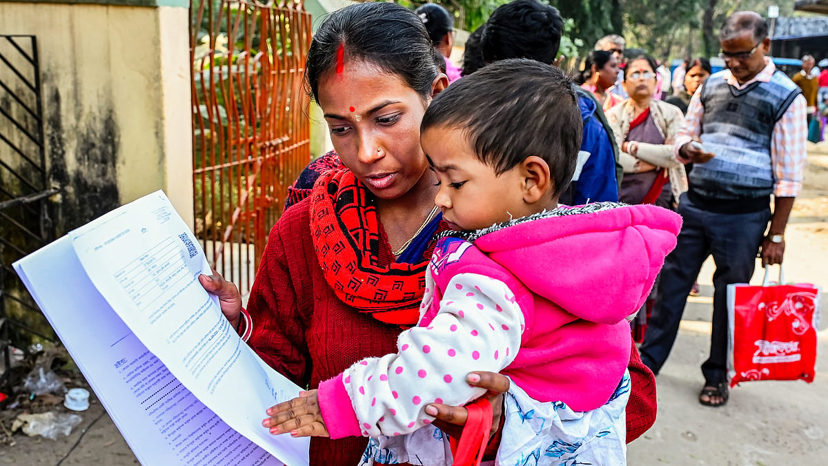 A woman carries a toddler as she waits to be enrolled, in Nadia, West Bengal, 14 Jan