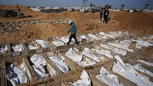 A man passes freshly dug graves holding the bodies of unidentified Palestinians.