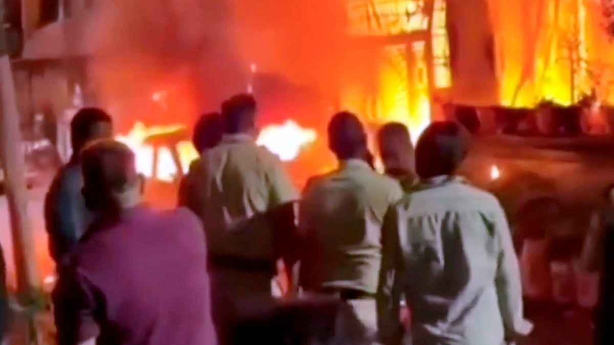 Onlookers gather as flames engulf a house in Indore.