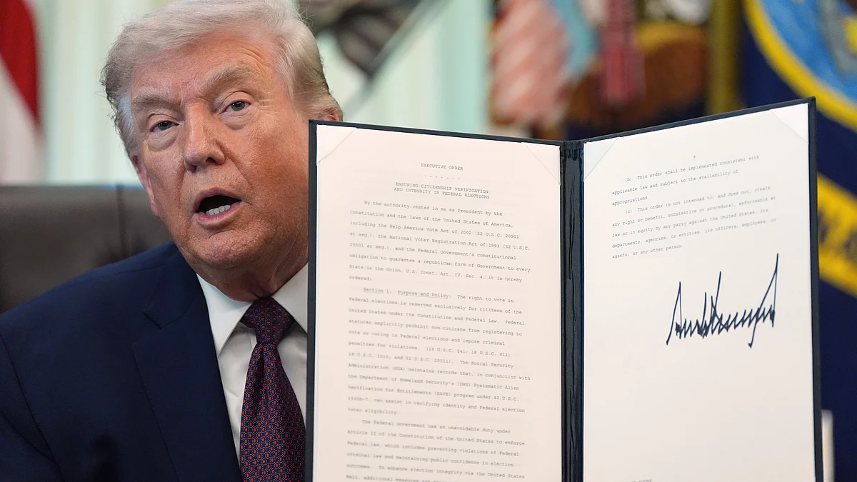Donald Trump holds a signed executive order at Oval office.