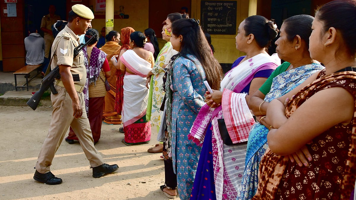 Policeman keeps vigil as people queue up to cast votes during Assam Assembly elections.