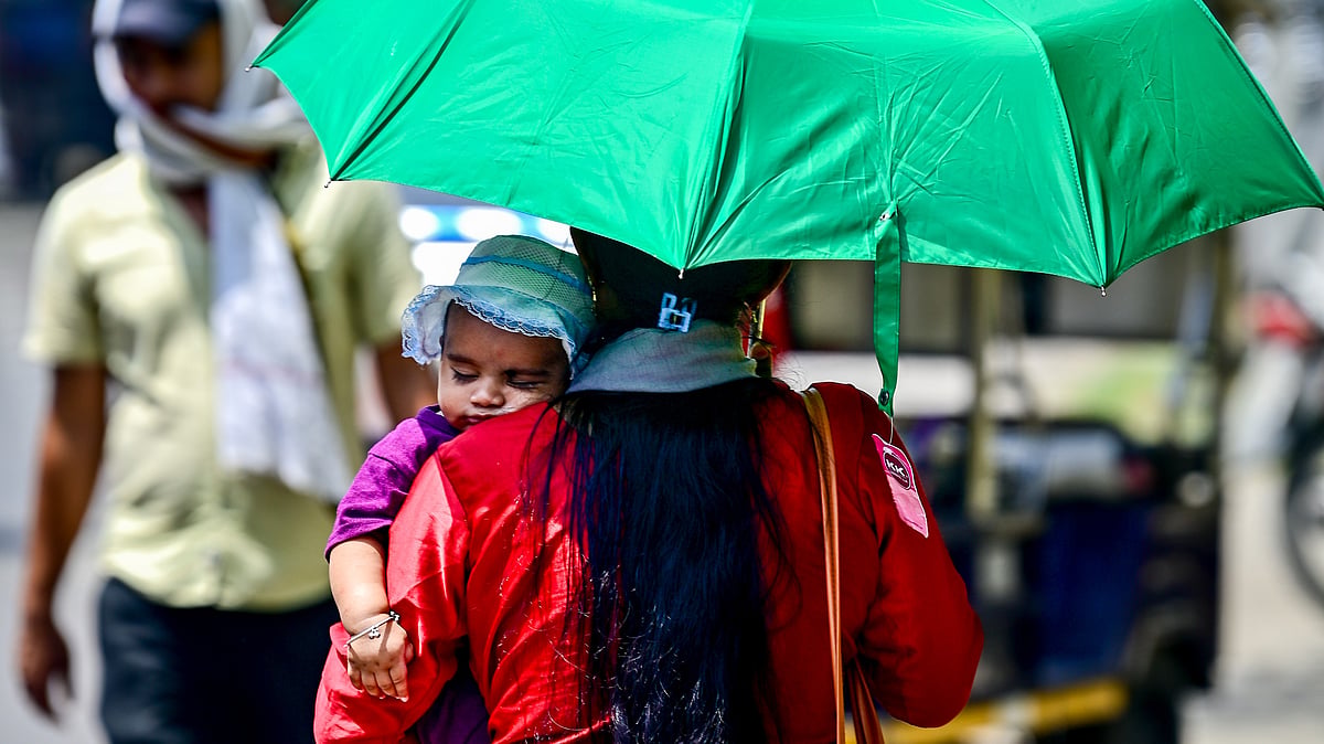 A woman shields her child from the scorching summer heat.