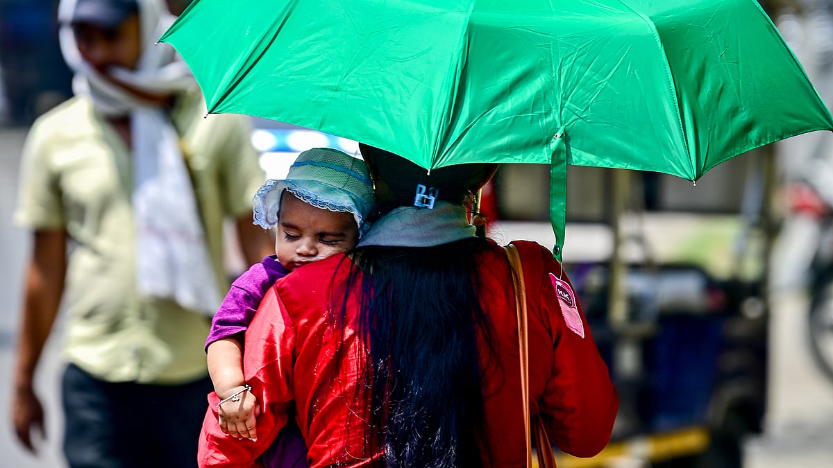 A woman shields her child from the scorching summer heat.