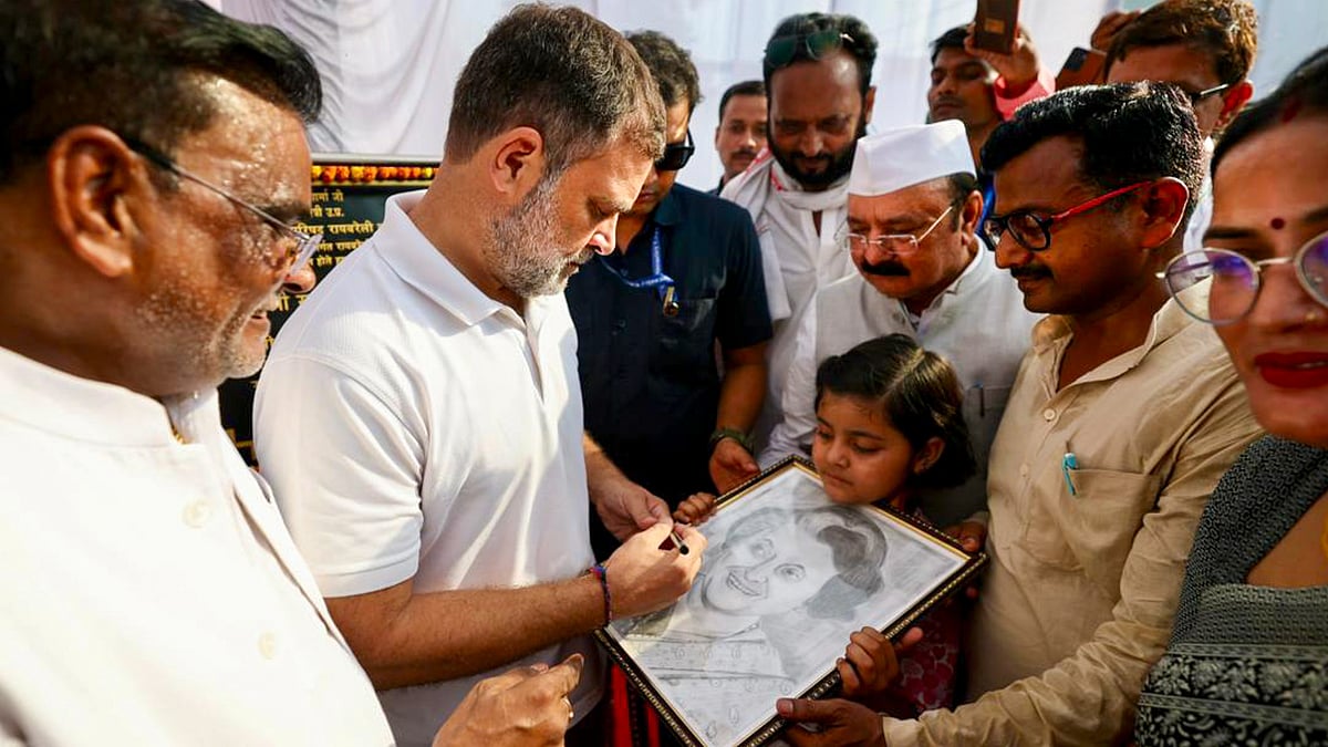 Rahul Gandhi signs a portrait of Indira Gandhi held by a girl during his visit to Raebareli