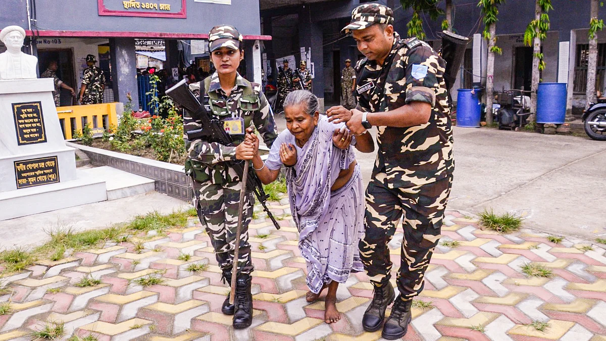 Security personnel assist a voter at a polling station during the Falta re-election