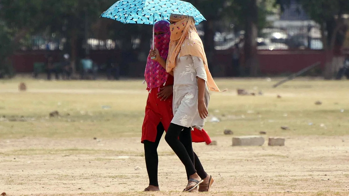 Young women walk under umbrellas to protect themself from scorching heat in Patna.