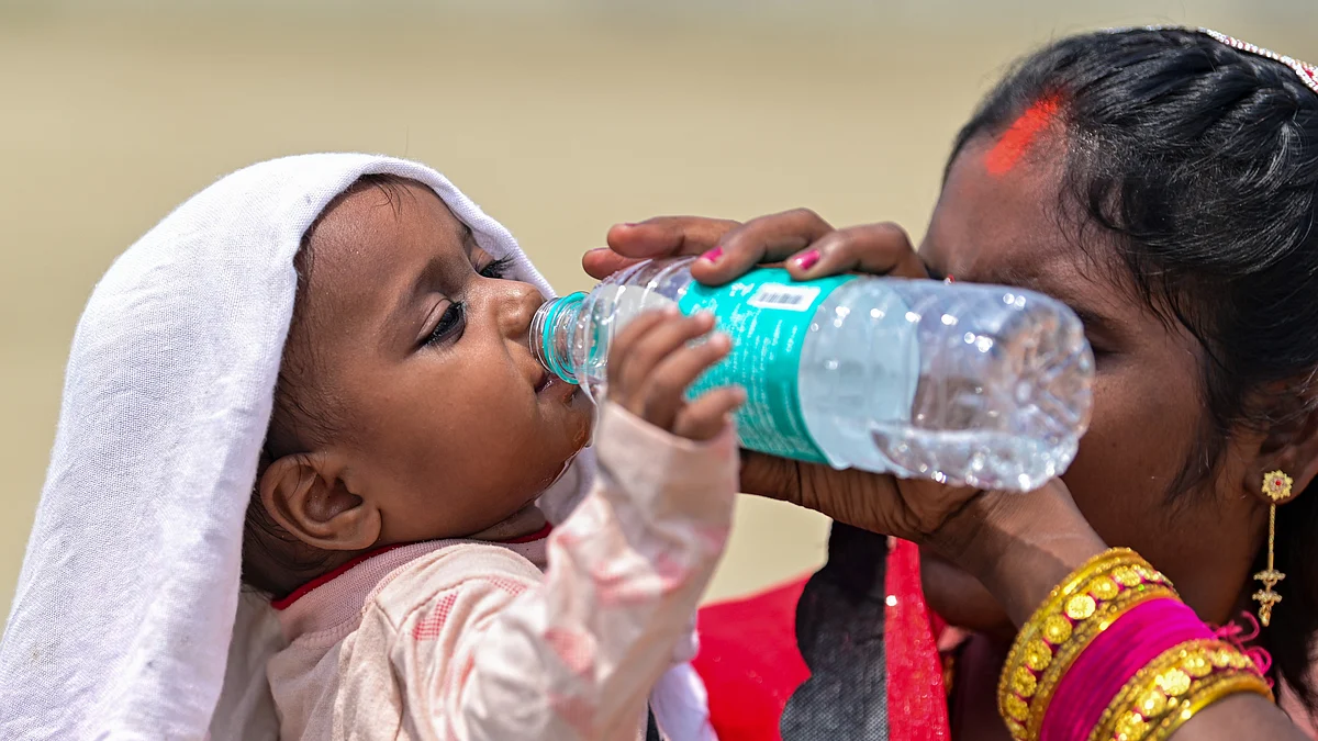 A woman offers water to a child amid scorching summer heat, in Prayagraj, Uttar Pradesh.