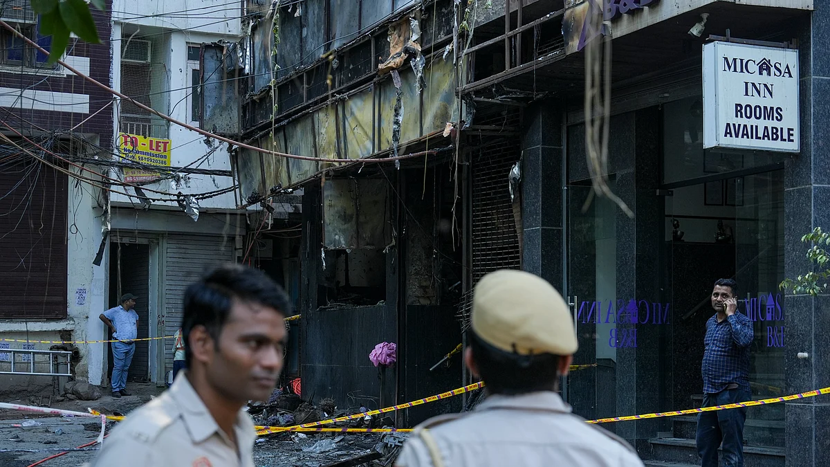 Police personnel stand guard near the site of a fire at a hotel in the Malviya Nagar area