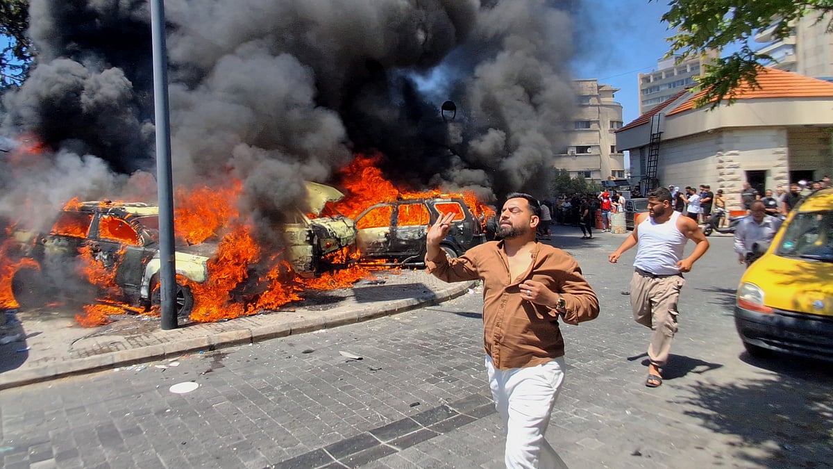 People run past cars damaged in an Israeli airstrike in Sidon, Lebanon.