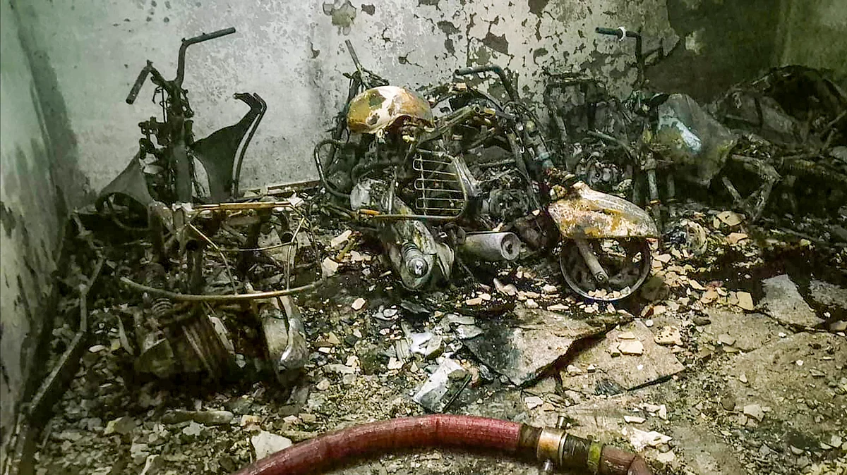 Charred vehicles lie amid debris after a fire engulfs a residential building in Delhi.