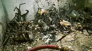 Charred vehicles lie amid debris after a fire engulfs a residential building in Delhi.