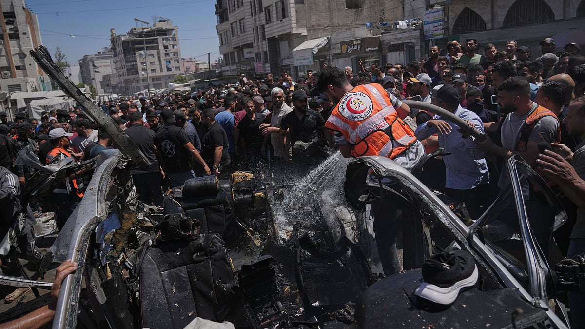 Palestinians gather around a car damaged in an Israeli strike in Gaza City.