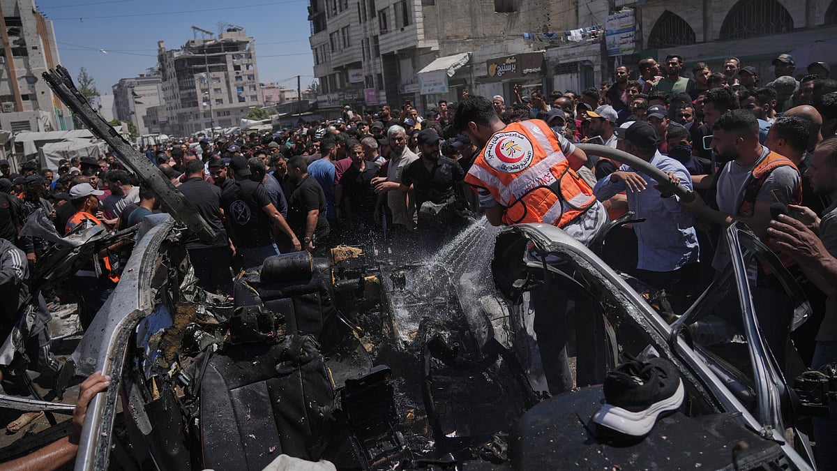 Palestinians gather around a car damaged in an Israeli strike in Gaza City.