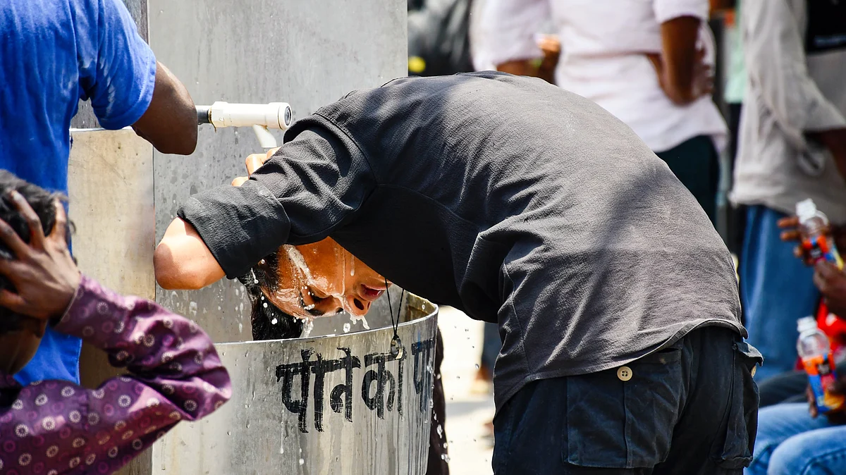A passenger cools himself at a drinking-water facility at Prayagraj railway station