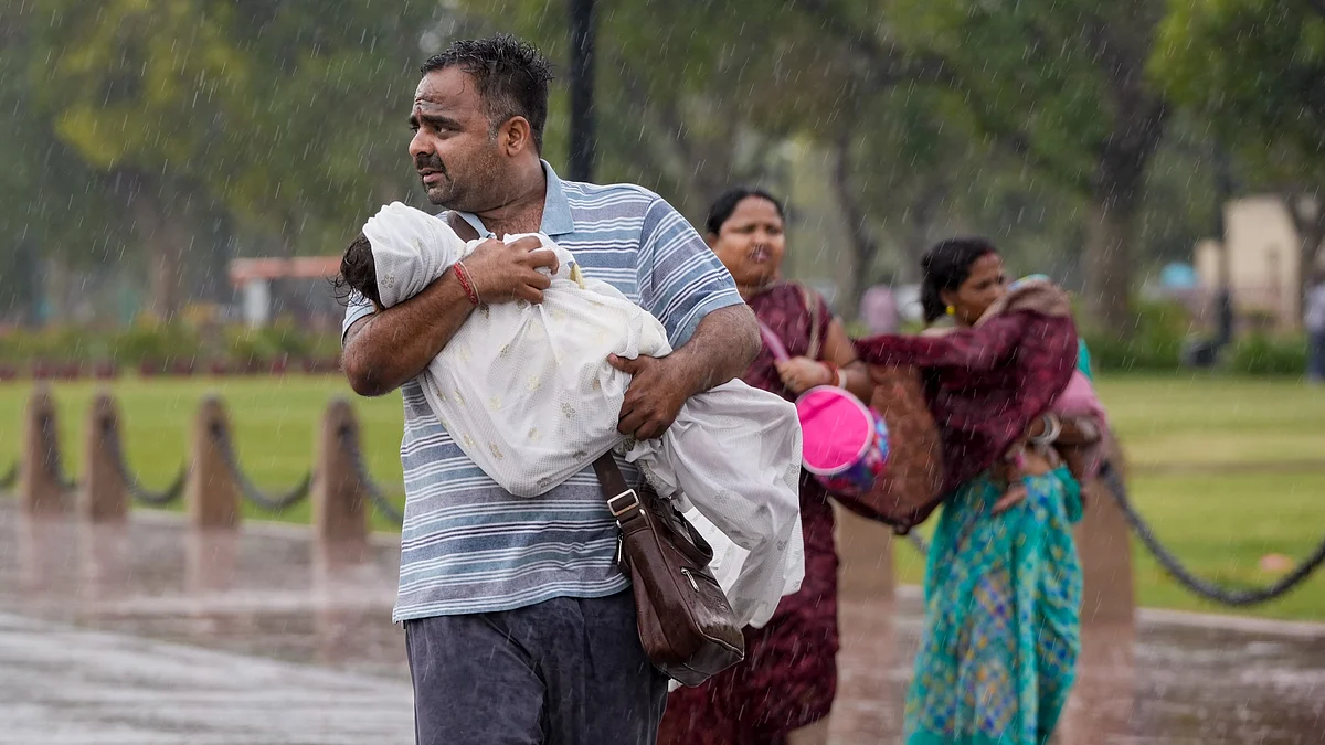 A man covers his child amid rain, near India Gate in New Delhi.