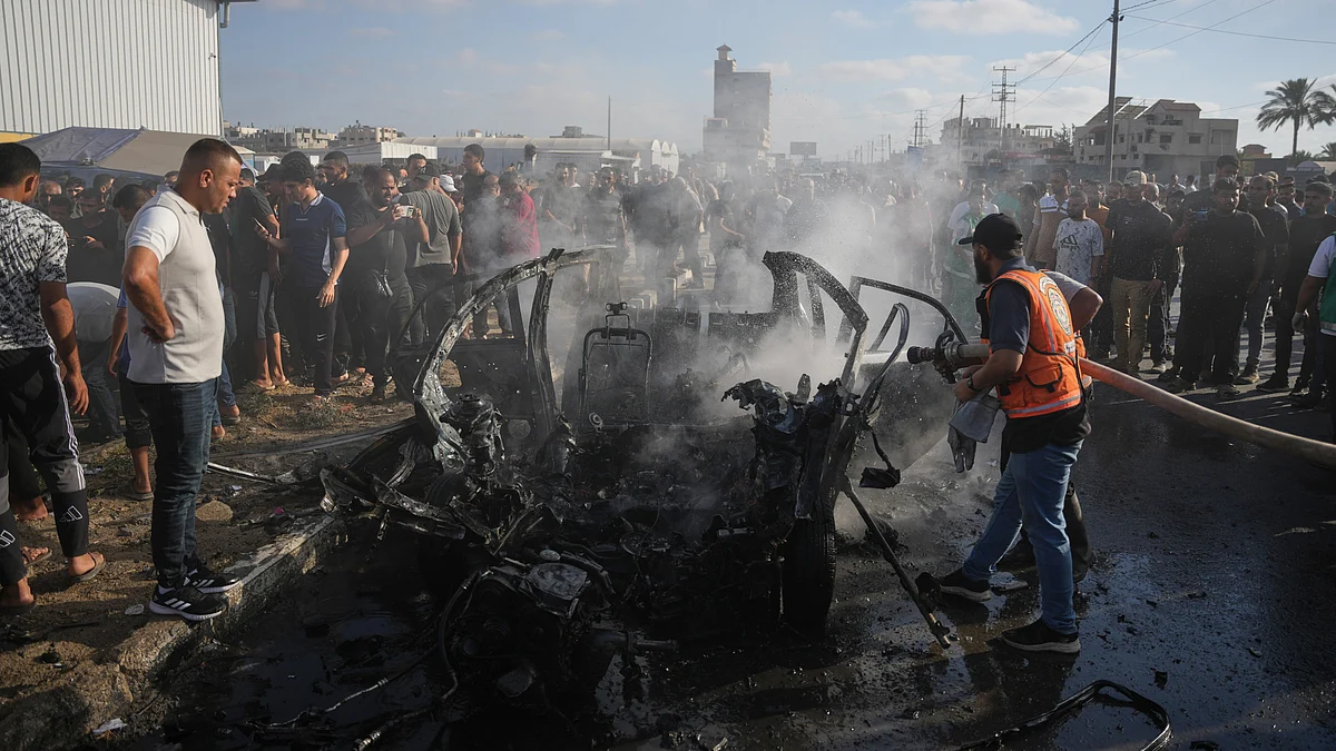 Palestinian civil defence personnel inspect a destroyed vehicle in central Gaza Strip.