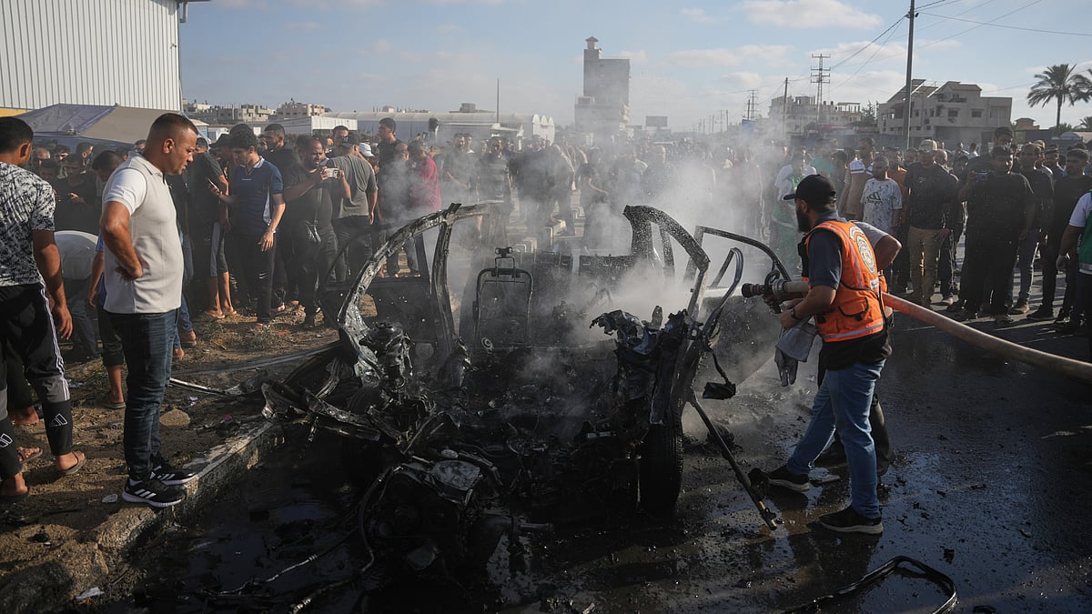 Palestinian civil defence personnel inspect a destroyed vehicle in central Gaza Strip.