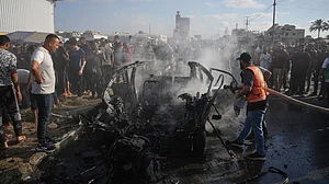 Palestinian civil defence personnel inspect a destroyed vehicle in central Gaza Strip.