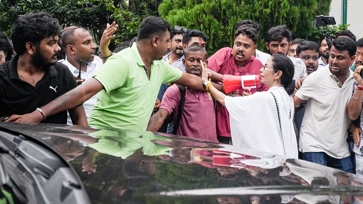 Mamata Banerjee directs party workers as they carry an injured worker (unseen) towards a car