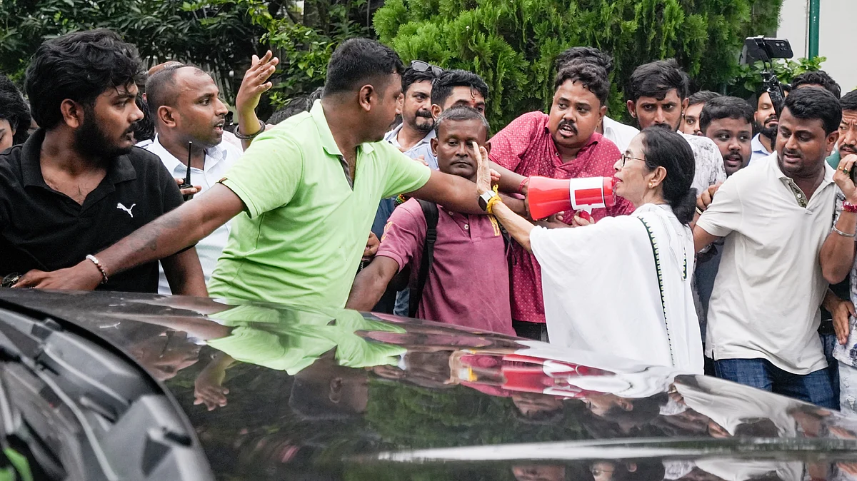 Mamata Banerjee directs party workers as they carry an injured worker (unseen) towards a car