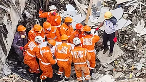 NDRF personnel carry a victim’s remains after Pune waste plant collapse.