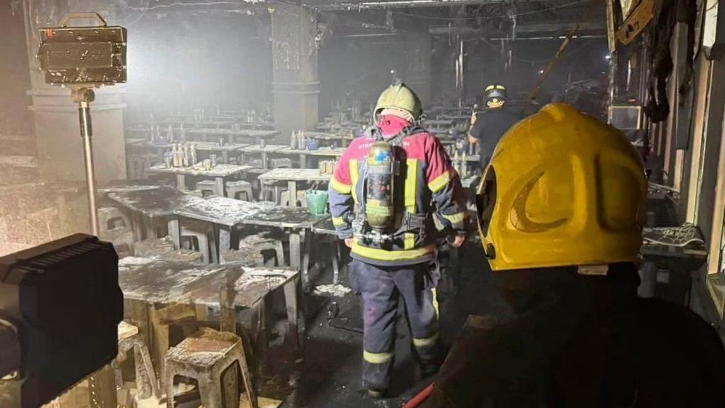 Firefighters walk through the remains of the Bangkok pub