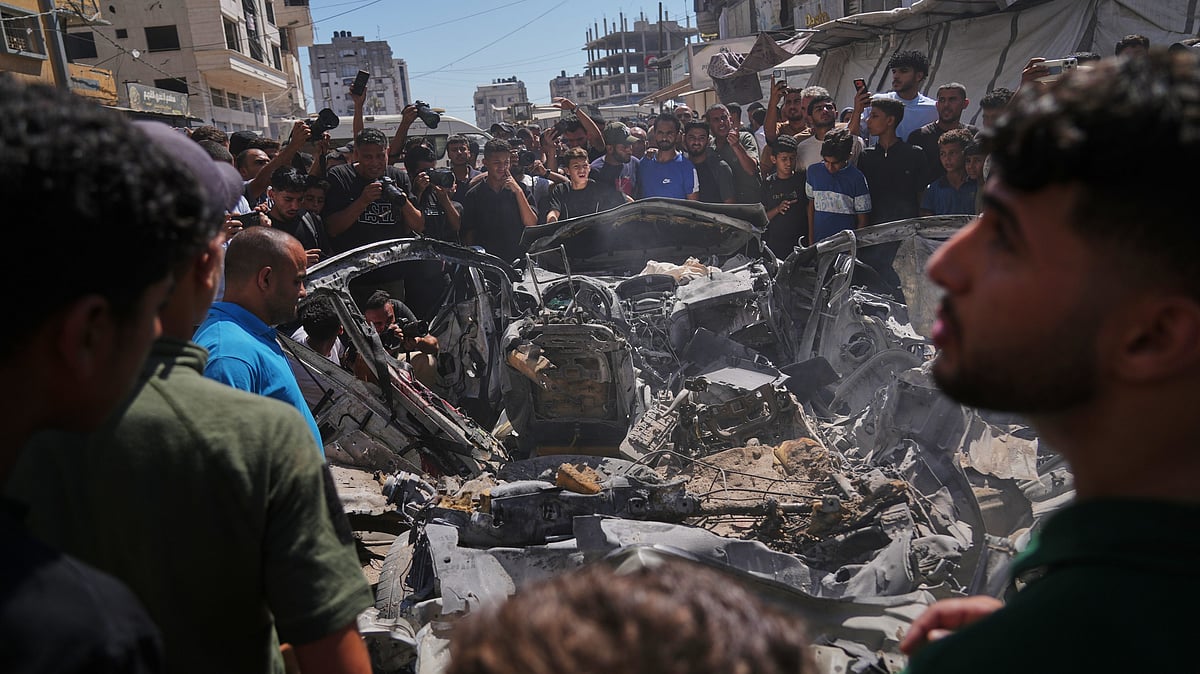 Palestinians gather around a vehicle destroyed in an Israeli strike in Gaza City.