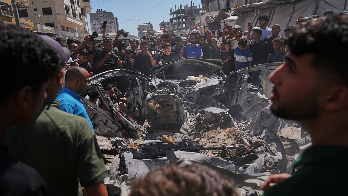 Palestinians gather around a vehicle destroyed in an Israeli strike in Gaza City.