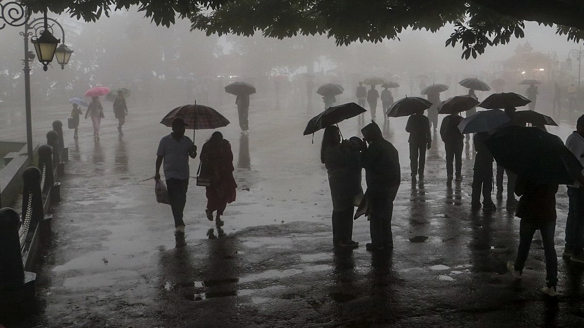 People walk on a misty, rain-soaked evening in Shimla.