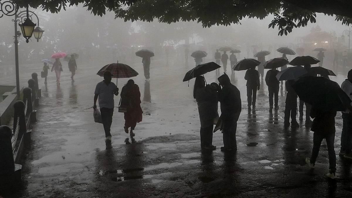People walk on a misty, rain-soaked evening in Shimla.