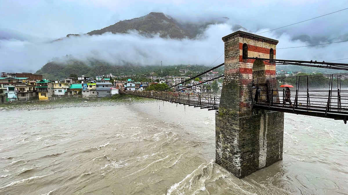 People cross a bridge over the swollen Beas in Bhuntar, Kullu.