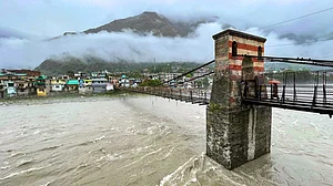 People cross a bridge over the swollen Beas in Bhuntar, Kullu.