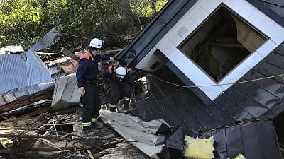 A rescue worker looks at a collapsed house.