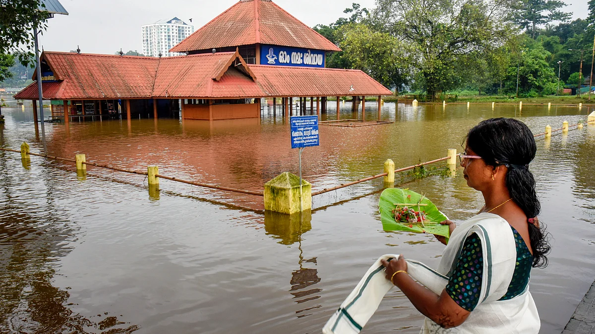 A woman offers prayers at Aluva Siva Temple as floodwaters recede in Kochi, 2 Aug