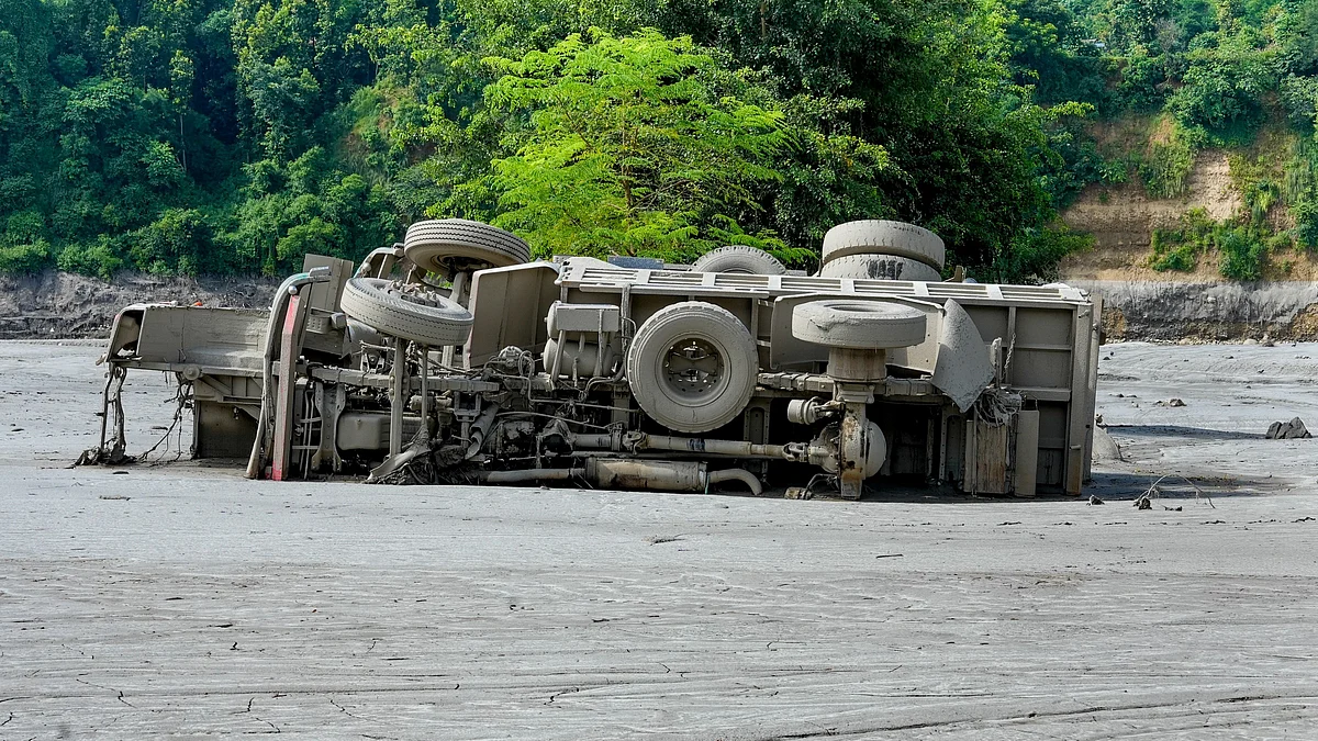 A truck lies overturned and partially buried in thick mud and debris following flash floods.