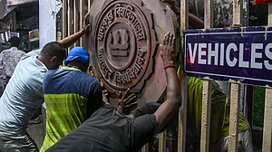 Workers reinstall the Jadavpur University emblem at the main gate.