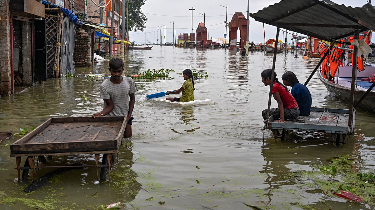 People wade through a flooded area in Prayagraj.