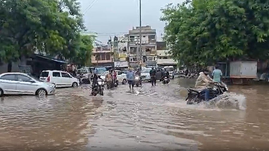Commuters make their way through a flooded street in Satna.